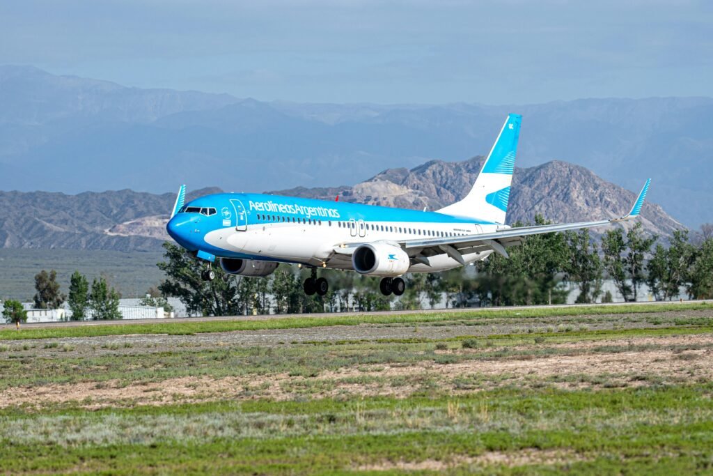 Aerolíneas Argentinas airplane landing with mountains in the background and clear skies.